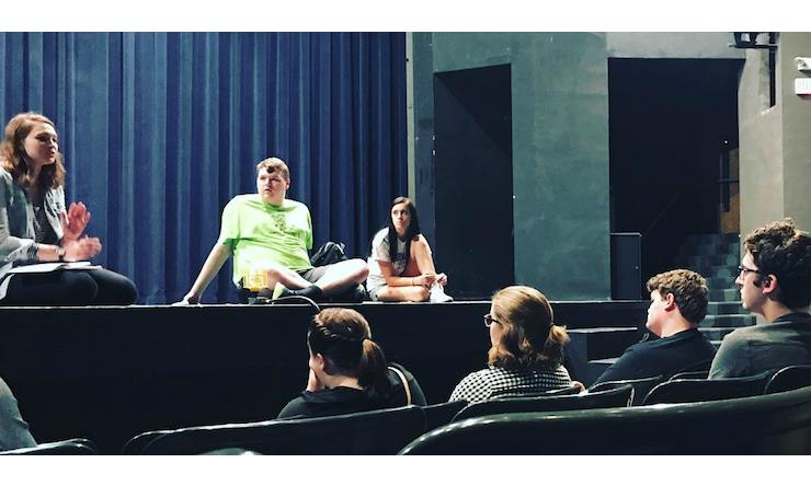 three people sitting on stage