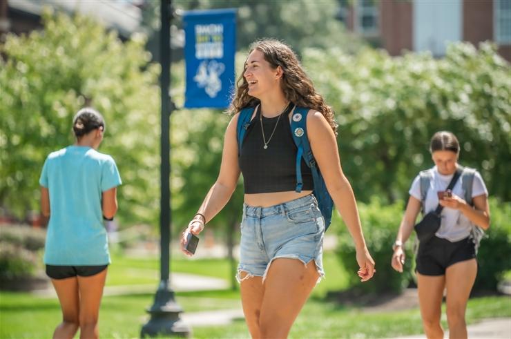 young woman walking across campus on the first day of classes